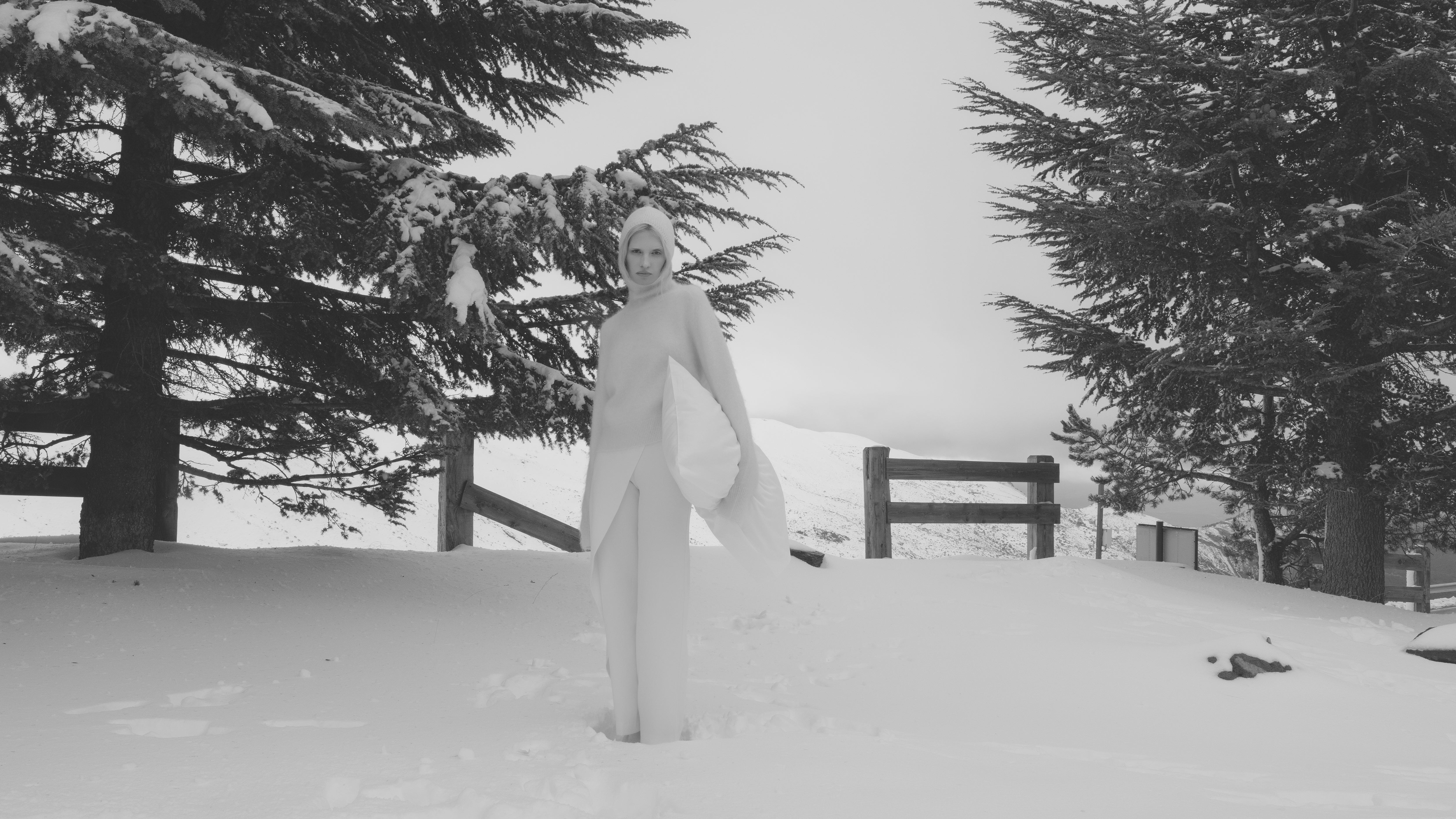 Woman standing in a snowy landscape in a black and white photo.