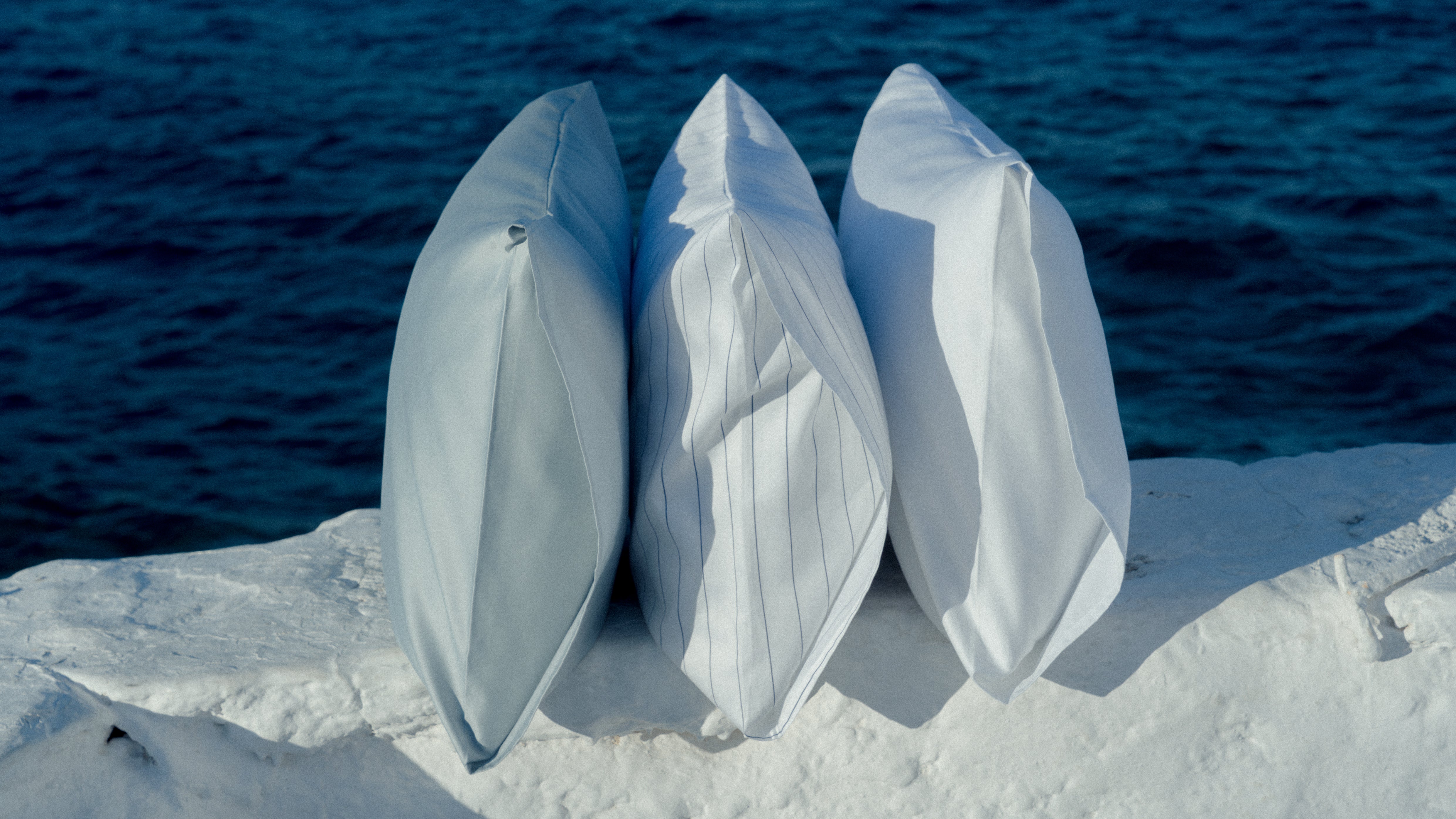 Abate pillows standing next to each other infront of the blue ocean
