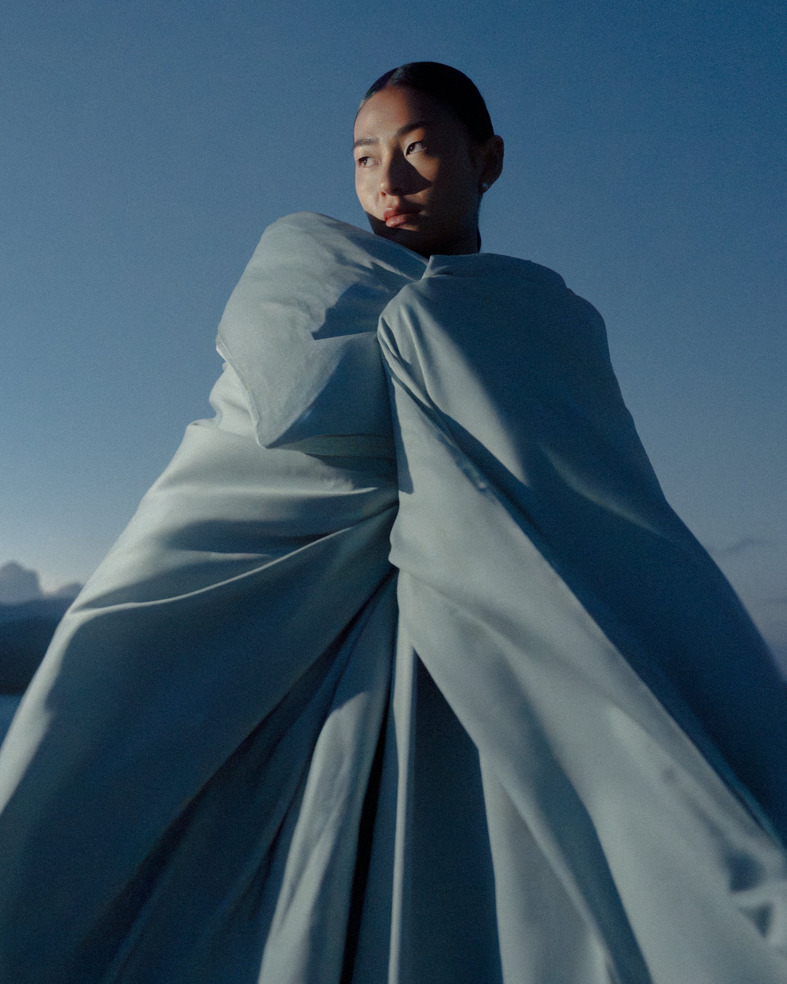 Kvinde med en stor luftig dyne omkring sig.